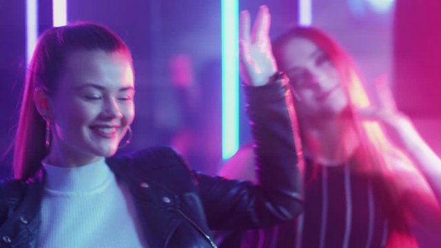 Neon women. Party lifestyle. Amused teen girls enjoying dancing in purple lights.