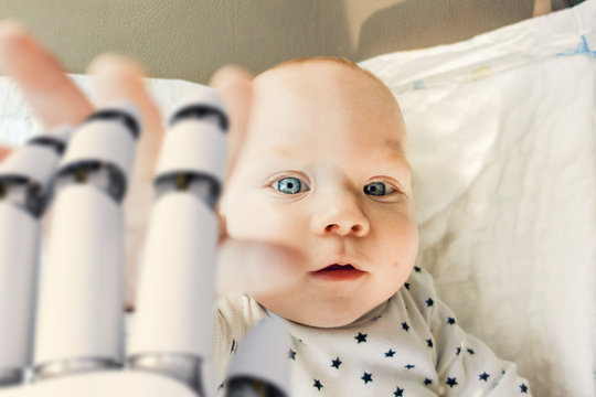 Portrait of baby boy reaching for robot hand
