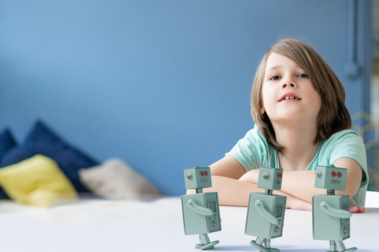 Portrait of boy with three toy robots