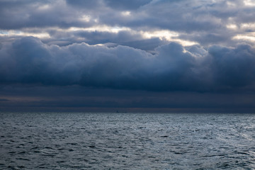Fototapeta premium blue dark stormy clouds above the sea and ship on the horizon