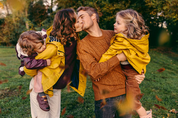 Couple kissing outdoors in autumn watched by her daughters