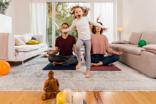 Exuberant girl with parents meditating at home
