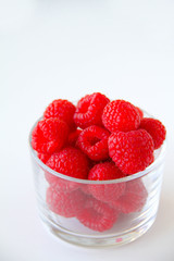 Fresh raspberries in a small glass on a white background. Healthy eating. Vegan food. Top view.