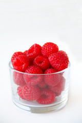 Fresh raspberries in a small glass on a white background. Healthy eating. Vegan food. Top view.