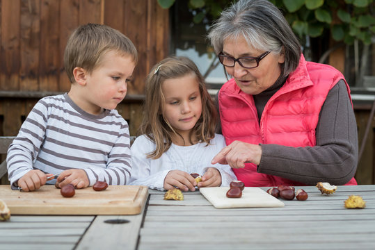 Two children and their grandmother tinkering with chestnuts