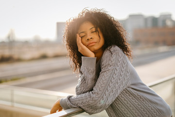 Beautiful young woman with closed eyes on a rooftop at sunset