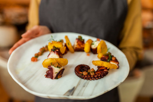 Waitress serving octopus and potatoes