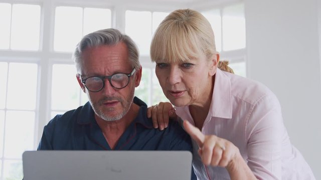 Senior Couple With Man In Wheelchair Looking Up Information About Medication Online Using Laptop