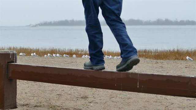 Man is standing on wooden fence walk and jump down