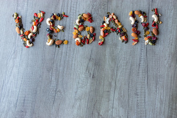 Vegan sur fond de bois avec le lettres en graines et fruits secs