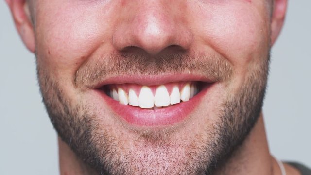 Close Up Of Mouth As Man With Perfect Teeth Smiles At Camera In Studio