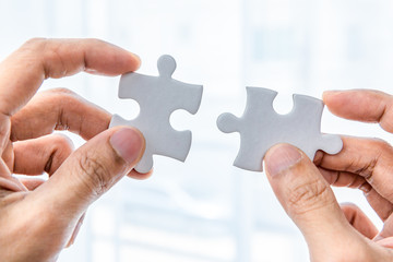 Hand holding two pieces of jigsaw connecting couple puzzle