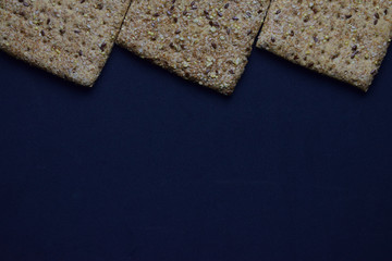 Semillas y cereales en panes cuadrados, sobre fondo azul oscuro