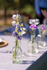 Decorative decoration of the festive table. Glass vases and fresh flowers. Decoration of holidays in the open air