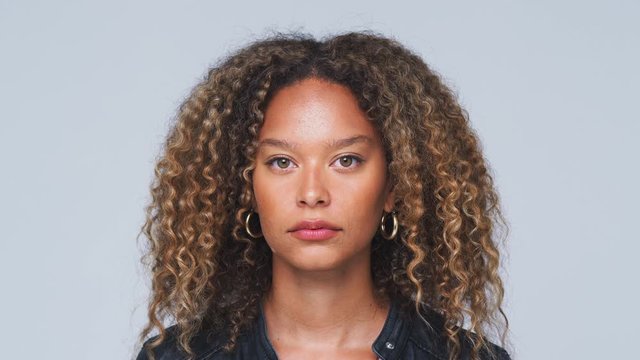 Head And Shoulders Studio Shot Of Woman Looking At Camera With Serious Expression In Slow Motion