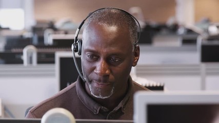 Mature Businessman Wearing Telephone Headset Talking To Caller In Customer Services Department - Powered by Adobe