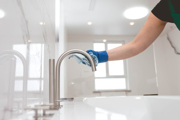  Girl in gloves cleans the faucet.  Bathroom cleaning