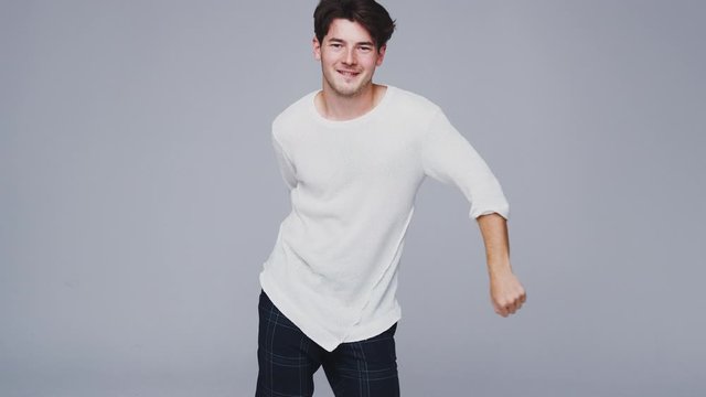 Wide Angle Studio Shot Of Young Man Against White Background Dancing And Flossing In Slow Motion
