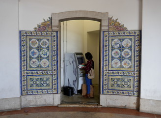 Young woman with black hair using an ATM to print bank statements and withdraw money. Lisbon, Portugal, Europe