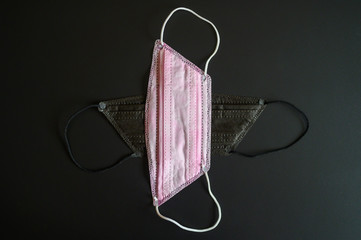 medical masks black and pink colors to cover the mouth and nose for protection from bacteria on a black background