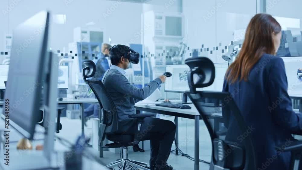 Poster Modern Factory: Industrial Design Engineer Wearing Virtual Reality Headset and Holding Controllers, Uses VR technology for Industrial Design, Development and Prototyping in CAD Software on Computer.