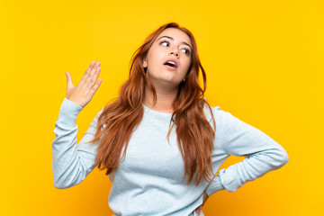 Teenager redhead girl over isolated yellow background with tired and sick expression