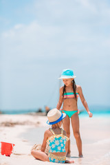 Two little happy girls have a lot of fun at tropical beach playing together