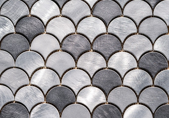 Metal mosaic tile in the form of scales. Silvery tile texture with marine design.