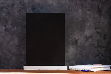 Chalk board mockup. Blackboard menu with easel on wooden table on a dark background. Copy space for...