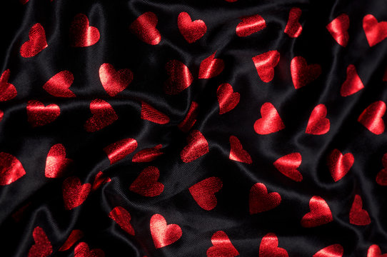 Shiny red love hearts folded into abstract black folded background
