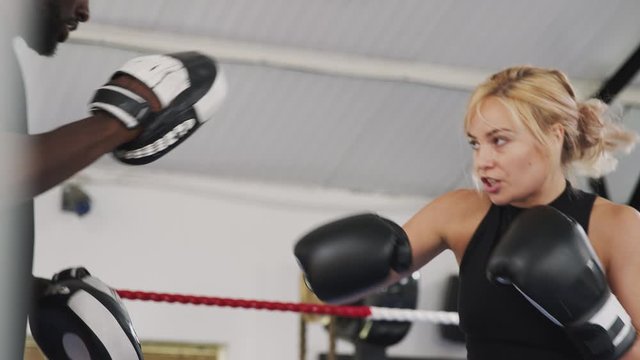 Male Boxing Coach With Female Boxer In Gym Using Training Gloves Sparring In Ring