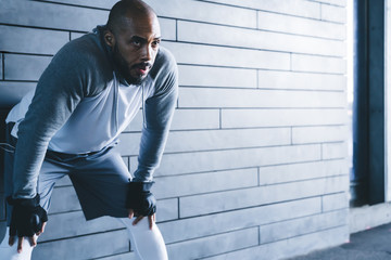Tired African American guy with hands on knees