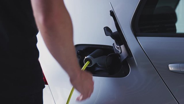 Close Up Of Hand Attaching Power Cable To Environmentally Friendly Zero Emission Electric Car 