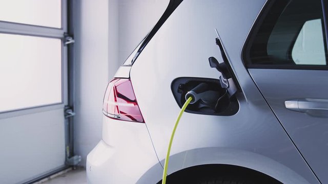 Close Up Of Power Cable Charging Environmentally Friendly Zero Emission Electric Car In Garage 