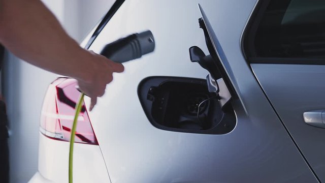 Close Up Of Hand Removing Power Cable From Environmentally Friendly Zero Emission Electric Car 