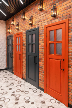 Four Multi-colored Colored Beautiful Doors To Enter The Toilet, Against The Background Of A Brick Wall And Beautiful Lanterns.