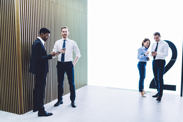 Fototapeta premium Multiracial coworkers using smartphones at office hall