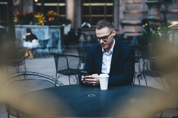 Manager using smartphone while drinking coffee at cafe