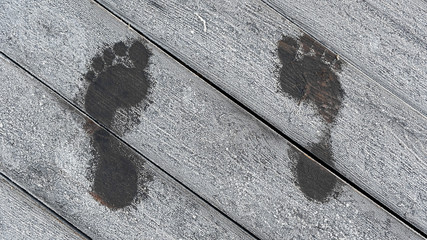 a warm trace from bare feet, footprints of a person with fingers on a wooden background, a dark...