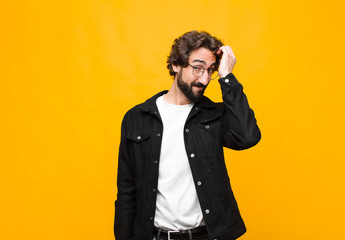young crazy handsome man smiling cheerfully and casually, taking hand to head with a positive,...