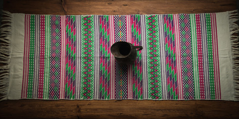 Camino de mesa con jarra de cobre encima sobre fondo de madera