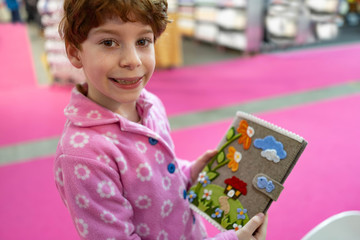 Bambina sorridente in rosa con libro e diario di scuola con disegni floreali