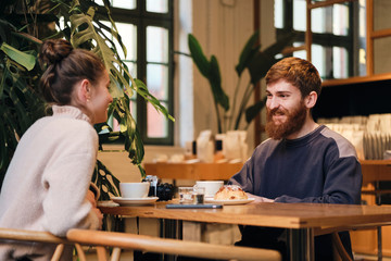 Young casual couple joyfully drinking coffee resting together in cafe