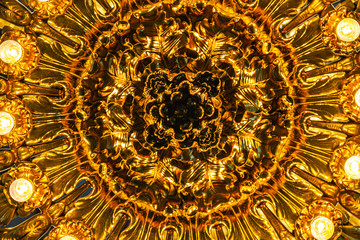 Abstract image looking up at a lite chandelier with golden accents.