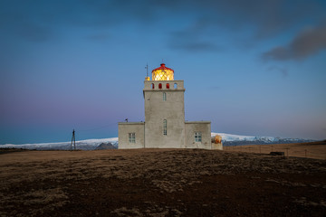 Fototapeta na wymiar Dyrholaey lighthouse over black sand beach in Iceland