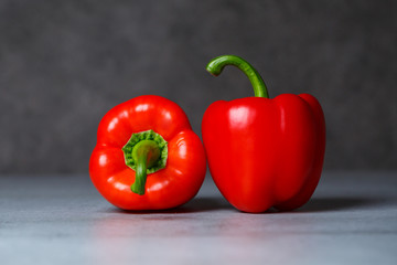 Two red peppers on a grey table
