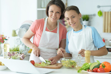 Obraz na płótnie Canvas Mother and son making fresh salad at kitchen
