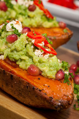 Healthy food - Baked sweet potatoes served with guacamole, feta cheese and pomegranate