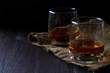 alcoholic drinks. glass of whiskey with ice on a black background. two glasses of whiskey on a wooden table with burlap. horizontal orientation