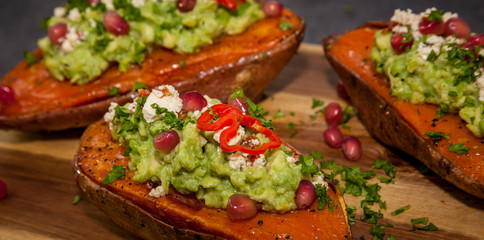 Healthy food - Baked sweet potatoes served with guacamole, feta cheese and pomegranate